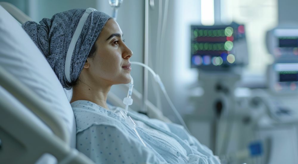 A woman in a hospital bed with PowerPort looking thoughtful in a healthcare setting.