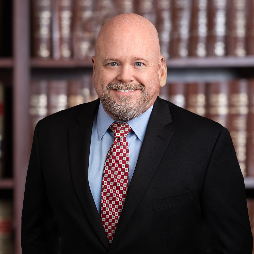 Business professional in suit smiling in front of bookshelves. Ideal for corporate or legal website.