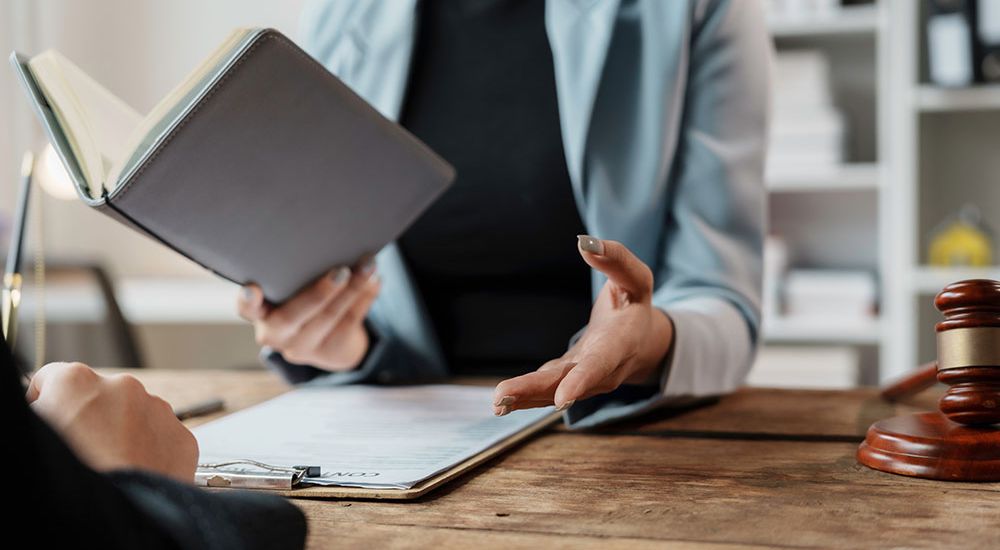 Person discussing legal documents in office with gavel on table.