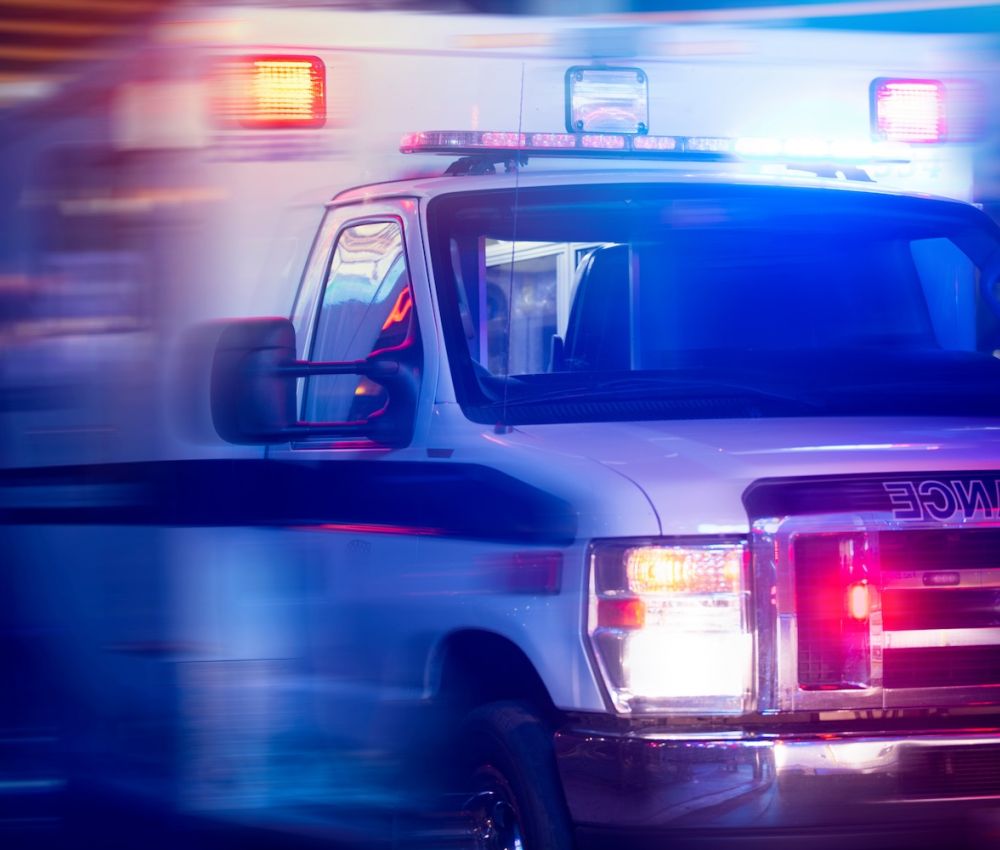 Emergency ambulance with flashing lights in motion at night.