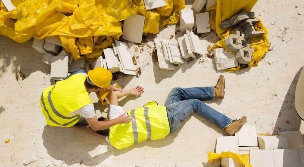 Two construction workers injured on the ground next to rubble