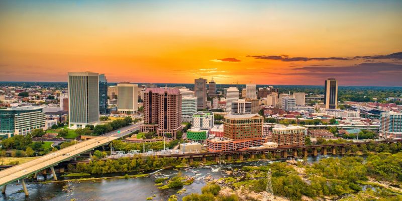 Aerial view of Richmond skyline at sunset with city buildings and river in foreground.