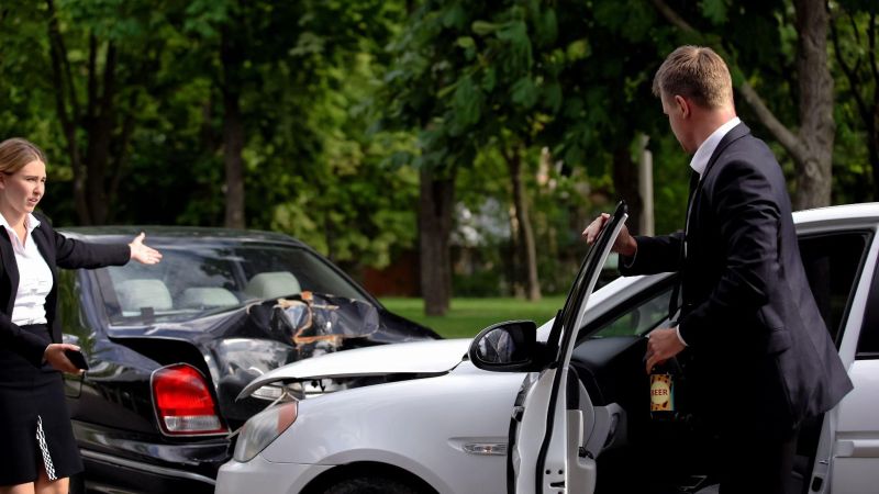 a man and a woman standing in front of their cars after a crash
