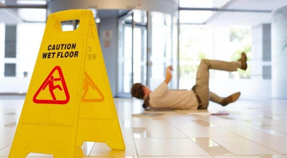 Man on floor next to wet floor sign