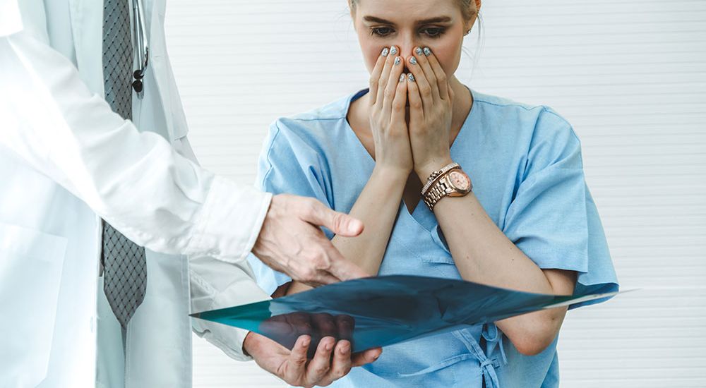 Doctor showing concerned patient an X-ray result in a medical office.