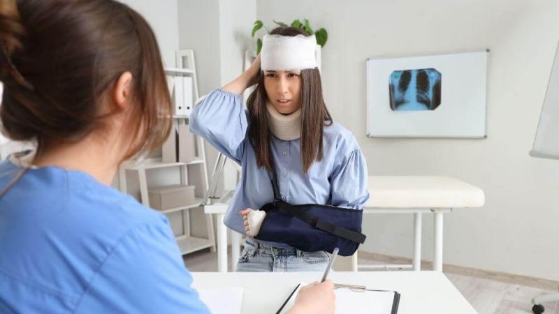 Woman with head cast at desk, reflecting