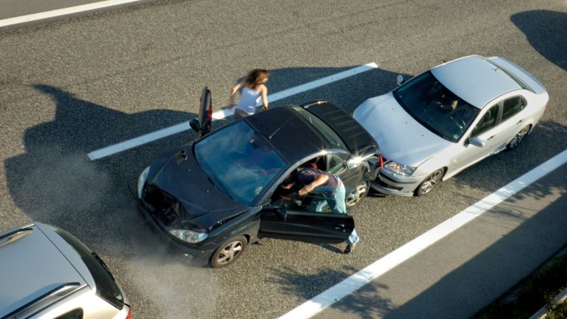 Two cars crash on a highway.