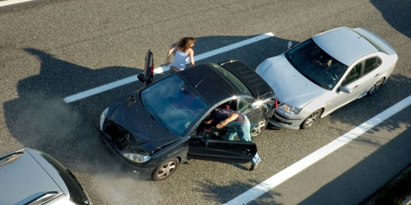 Two cars crash on a highway.