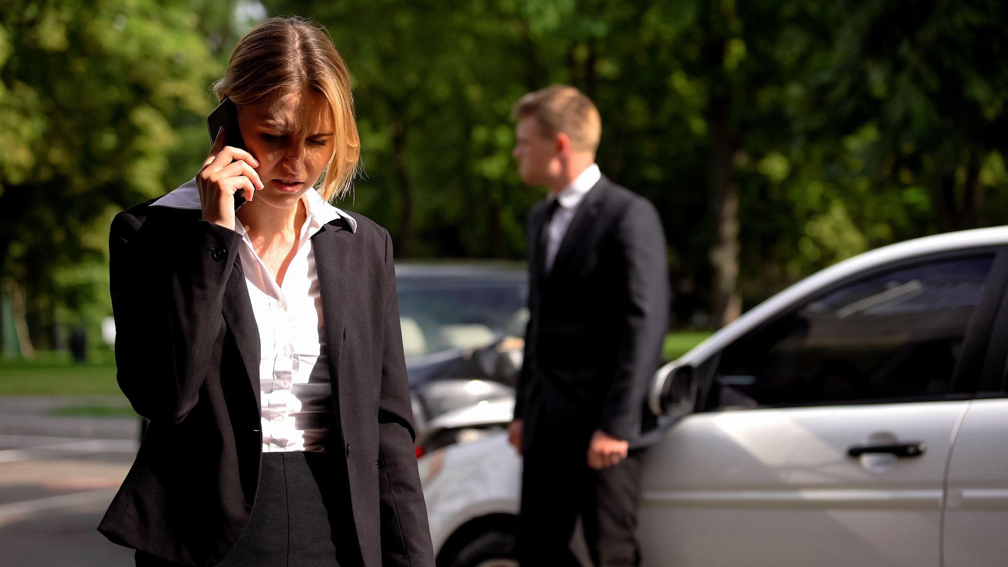 a woman talking on a cell phone next to a man in a suit
