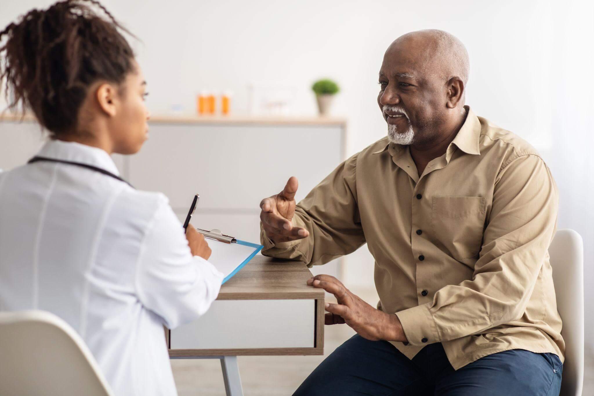 Doctor talks to patent at desk about medical