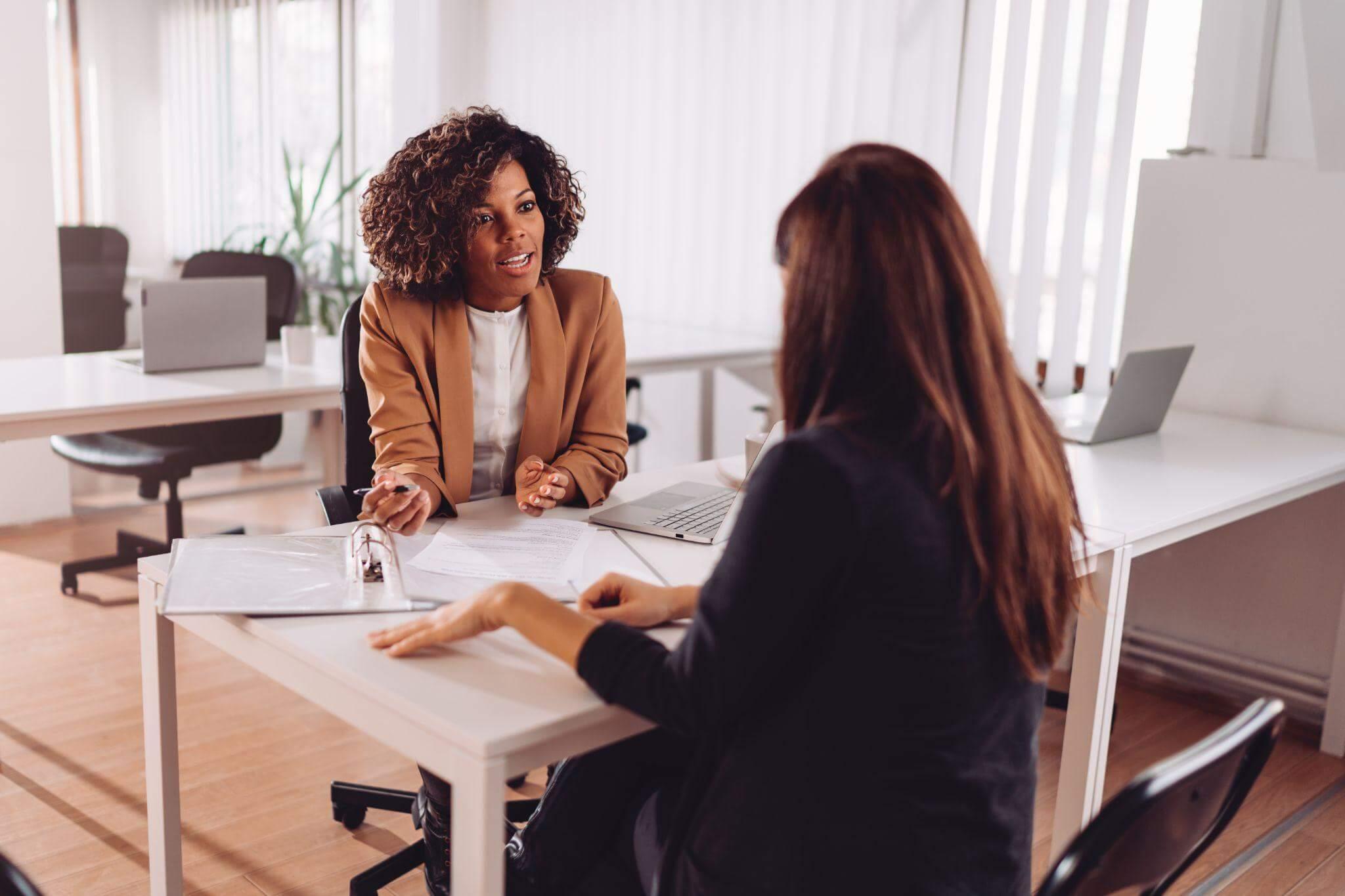 Two women discussing a client review about a car