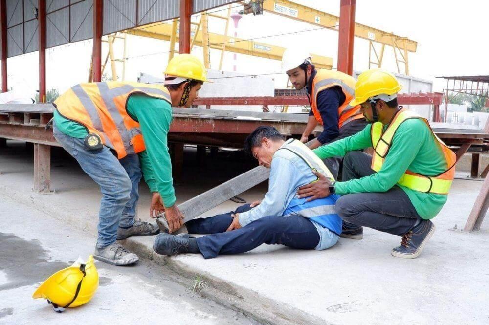 Group of men around an injured worker at a construction